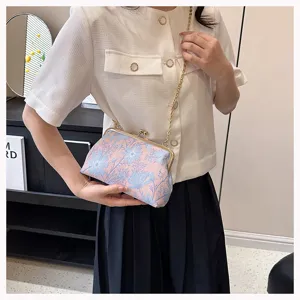 Nahaufnahme der Vintage-Tasche mit Blumenstickerei und elegantem goldenen Kettengurt