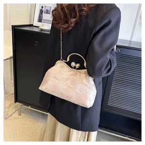 Primer plano del elegante bolso bordado con flores y cierre de perlas usado por la modelo