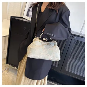 Detalle de elegante bolso bordado de flores con cierre de perla y correa de cadena.