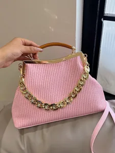 Elegant pink woven handbag featuring a chunky gold chain and acrylic top handle
