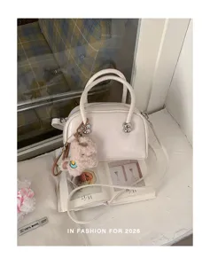 Detailansicht der cremeweißen Kissen-Tasche mit stilvollem Plüschanhänger und Silberbeschlägen