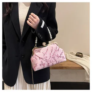 Detailansicht der rosafarbenen Abendtasche mit Blumenstickerei und Perlengriff.