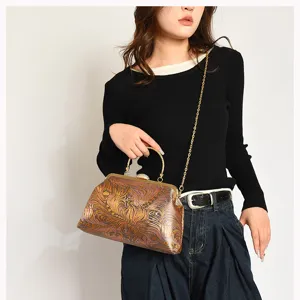Elegante Vintage-Clutch mit Stickerei und goldener Kette, von einem Modell getragen