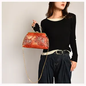 Elegante rote gemusterte Clutch mit goldener Kette, von einem Model getragen.