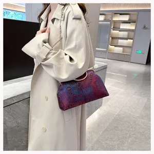 Elegante bestickte Abendtasche mit goldener Kette, an einem Model präsentiert.