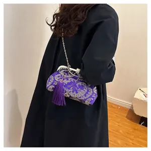 Borsa da sera viola con ricami floreali dorati e nappa, indossata da una modella.