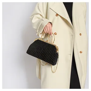 Detailansicht einer luxuriösen schwarzen Samttasche mit Goldkette, von einem Model gehalten