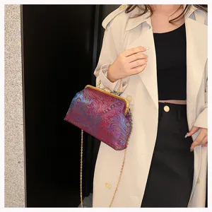 Model trägt eine lila Brokat-Abendtasche mit goldener Kette am Trenchcoat