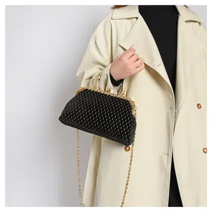 Detailansicht einer schwarzen Samt-Clutch mit goldenen Streifen auf beigem Mantel.