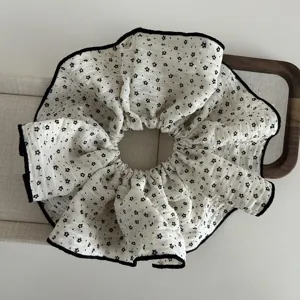Cream colored seersucker large hair scrunchie with black floral print and piped edges