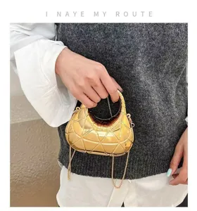 Macro view of gold geometric hard shell evening handbag showing metallic texture
