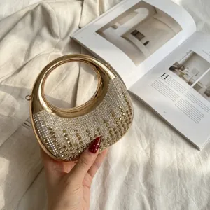 Primer plano de los brillantes adornos de pedrería en el elegante bolso de mano luna dorado.