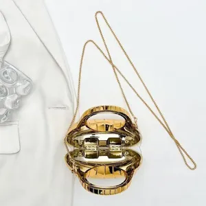 Close-up of a gold shell-shaped hard-shell evening clutch with a fine metal chain strap