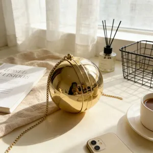 Detailed close-up of a golden spherical evening bag with elegant metal chain strap