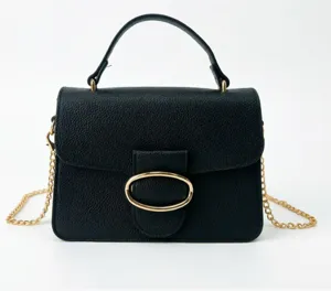 Detailed view of the elegant black textured handbag with golden circular buckle