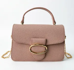 Front view of a pink pebble grain handbag with a gold oval buckle and chain