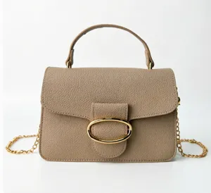 Close-up of textured beige leather handbag with gold oval buckle and chain