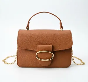 Detailed view of elegant camel leather handbag featuring gold oval buckle and chain strap