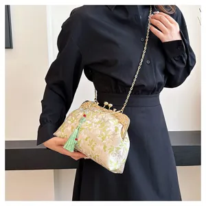 Detail view of a vintage-style embroidered crossbody bag with an elegant green tassel.