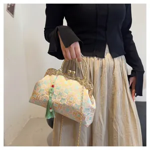 Close-up detail of vintage floral embroidered handbag with green tassel and gold chain strap