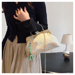 Detail of elegant embroidered crossbody bag with green tassel and gold chain strap