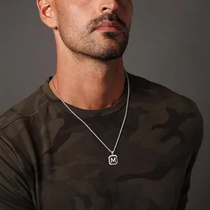 Gros plan détaillé d'un collier pour homme en acier inoxydable avec pendentif lettre M.