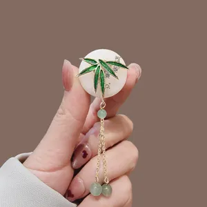 Close-up of elegant Chinese style jade ring brooch with green bamboo leaf and tassels