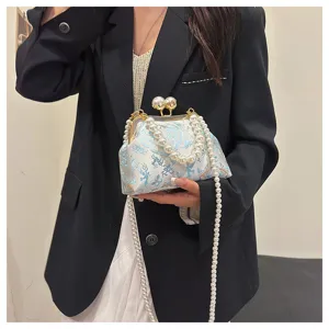 Elegante borsa qipao ricamata azzurra con tracolla di perle tenuta da una modella