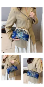 Nahaufnahme einer blau bestickten Abendtasche mit Goldkette und dekorativer Quaste.