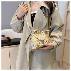Dettaglio ravvicinato di borsa da sera ricamata con eleganti manici di perle finta.