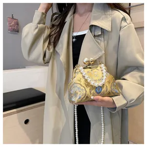 Dettaglio di una borsa da sera in broccato di seta giallo con manico di perle