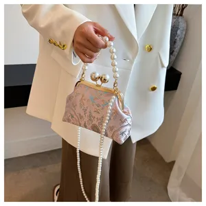 Dettaglio della borsa ricamata rosa con elegante manico di perle e tracolla lunga