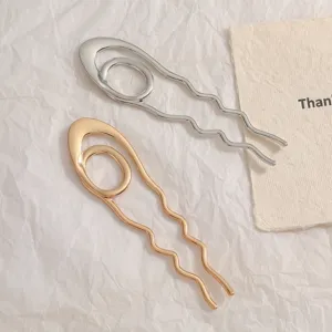 Close-up of minimalist wave-shaped U-hairpins in gold and silver finishes