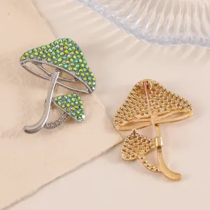 Detail view of mushroom brooches with green rhinestones and golden pin back