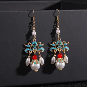 Gros plan de boucles d'oreilles chinoises vintage avec perles et émail bleu.