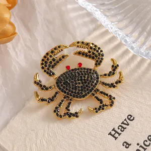Detailed view of an ornate gold-tone crab brooch featuring black rhinestones and red eyes.