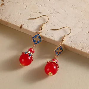 Détail macro de boucles d'oreilles de style chinois avec perles rouges et motifs nuages.