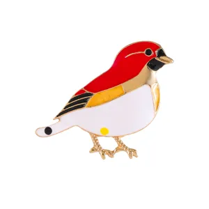 Macro view of an elegant red and white enamel bird brooch with a polished gold-toned finish