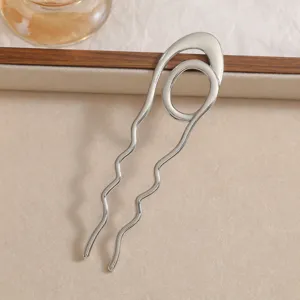 Close-up view of a minimalist silver wavy U-shaped hair fork for elegant updo styles.