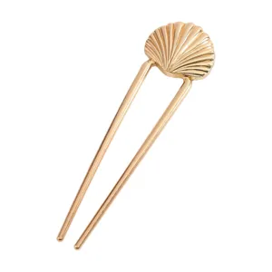 Close-up of a golden U-shaped hair fork featuring a minimalist seashell design for hair styling