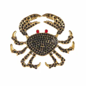 Close-up detail of a vintage-style gold crab brooch with black and red rhinestones