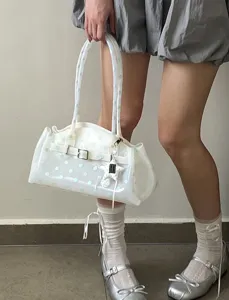 Detailed view of a white translucent polka dot jelly handbag held by a model in daily style