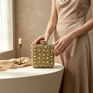 Elegant luxury gold evening clutch bag with sparkling yellow gemstones held by a lady