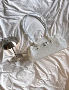 Detail shot of a white transparent jelly shoulder bag featuring mint green polka dots