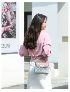Model wearing a luxury retro small square bag with chain strap and lock closure