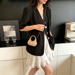 Detalle de un mini bolso de noche de perlas con cadena dorada usado por una modelo