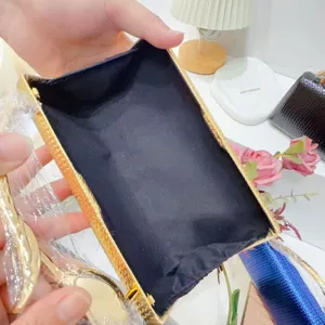 Close-up interior detail of gold evening clutch bag showing black lining and metal frame