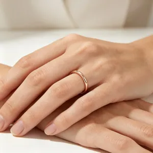 Gros plan détaillé d'un anneau minimaliste uni en or rose de 2 mm porté au doigt.