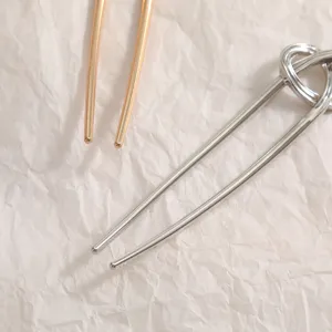 Vue rapprochée des pointes polies d'une épingle à cheveux en métal en forme de U argent.