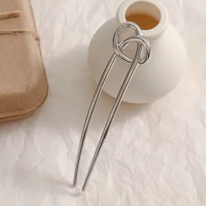 Gros plan sur une élégante épingle à cheveux argentée en U avec un design moderne de nœud.